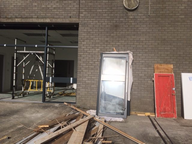 New windows and doors being fitted. Frame in and glass doors leaning against a brick wall.